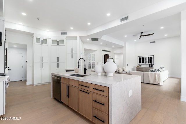 kitchen featuring a sink, stainless steel dishwasher, light wood-style floors, a center island with sink, and recessed lighting