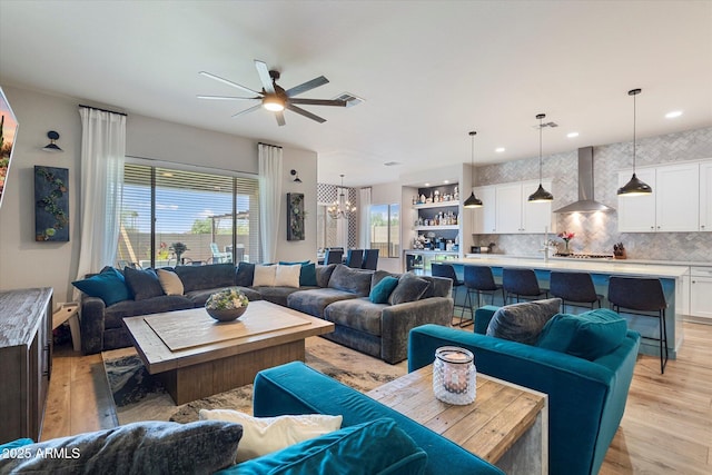 living area with ceiling fan with notable chandelier, light wood finished floors, visible vents, and recessed lighting