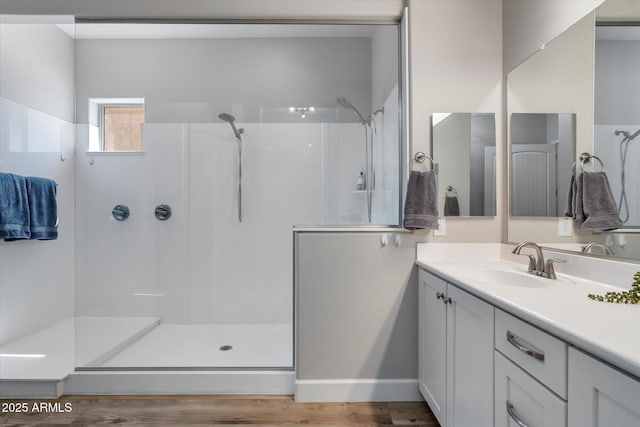 bathroom with baseboards, a walk in shower, vanity, and wood finished floors