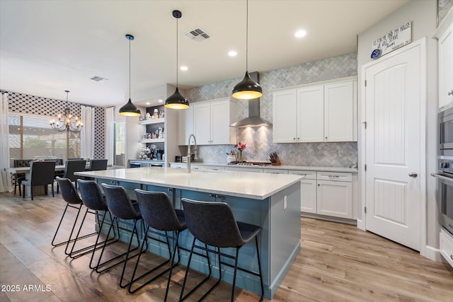 kitchen featuring visible vents, a chandelier, a sink, light wood finished floors, and a breakfast bar area
