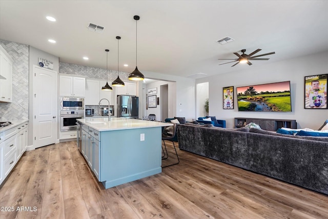 kitchen featuring white cabinetry, visible vents, appliances with stainless steel finishes, light countertops, and open floor plan