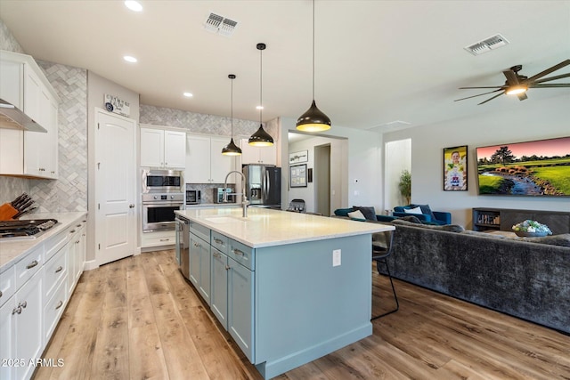 kitchen featuring white cabinets, open floor plan, visible vents, and appliances with stainless steel finishes