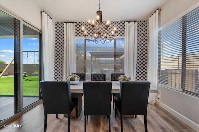 dining room featuring a chandelier, baseboards, and wood finished floors