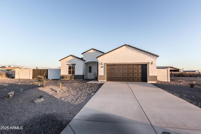 ranch-style home with fence, an attached garage, stucco siding, concrete driveway, and a tile roof