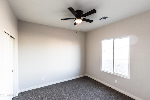 unfurnished bedroom featuring dark colored carpet, visible vents, baseboards, and a closet