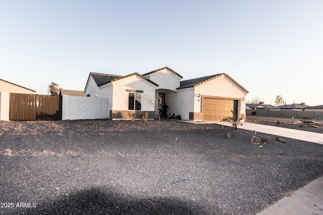 view of front of home featuring stucco siding, driveway, fence, a garage, and a tiled roof