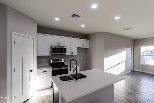 kitchen featuring stainless steel appliances, visible vents, and light wood-style flooring