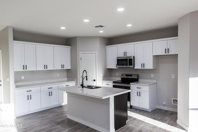 kitchen with visible vents, a kitchen island with sink, a sink, appliances with stainless steel finishes, and light wood finished floors