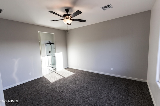 spare room with dark colored carpet, visible vents, baseboards, and ceiling fan