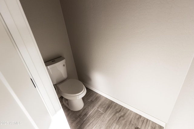 bathroom featuring wood finish floors, baseboards, and toilet