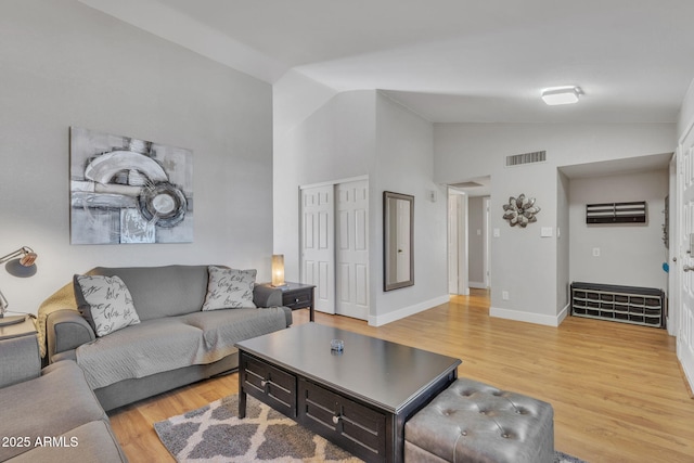 living room featuring high vaulted ceiling and light hardwood / wood-style flooring