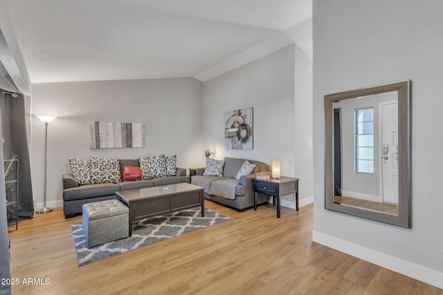 living room with vaulted ceiling and light wood-type flooring