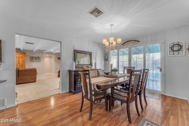 dining space with visible vents, a notable chandelier, baseboards, and wood finished floors