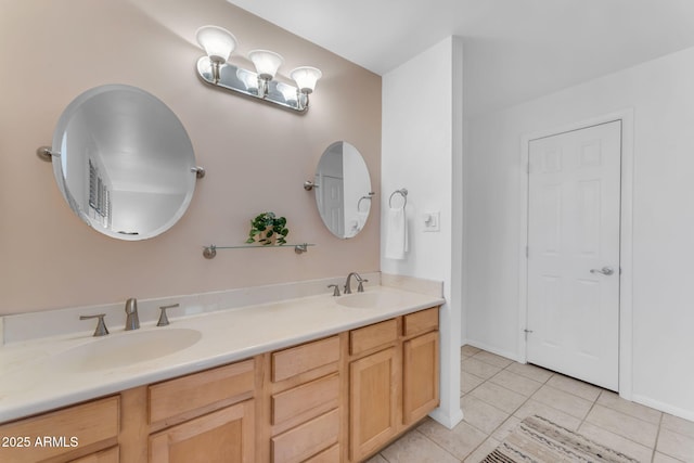 bathroom with double vanity, baseboards, a sink, and tile patterned floors