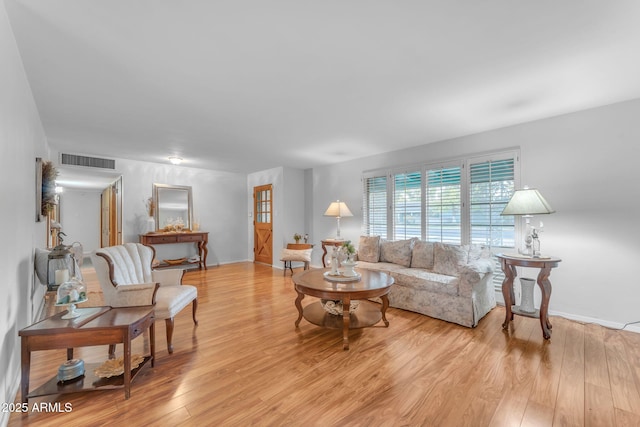 living area featuring light wood finished floors, baseboards, and visible vents