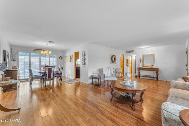 living room with a notable chandelier, visible vents, and light wood-style floors