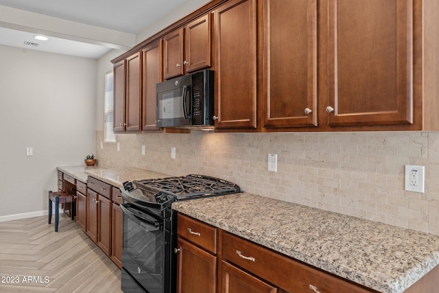 kitchen with light parquet flooring, backsplash, light stone countertops, and black appliances