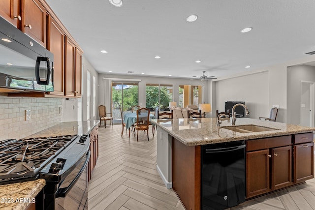 kitchen featuring light stone countertops, ceiling fan, black appliances, sink, and light parquet floors