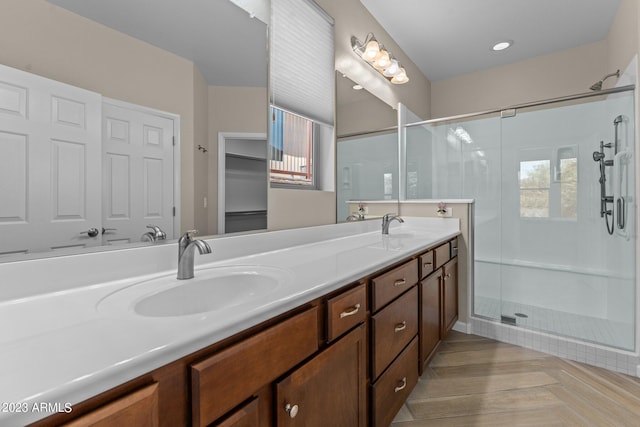 bathroom with dual bowl vanity and a shower with door