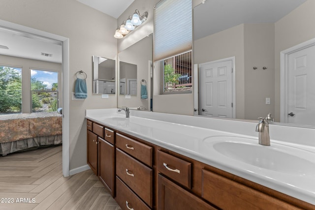 bathroom with parquet flooring, large vanity, and dual sinks