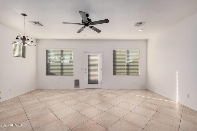 tiled spare room with ceiling fan with notable chandelier