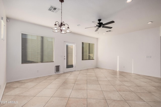 tiled spare room with ceiling fan with notable chandelier