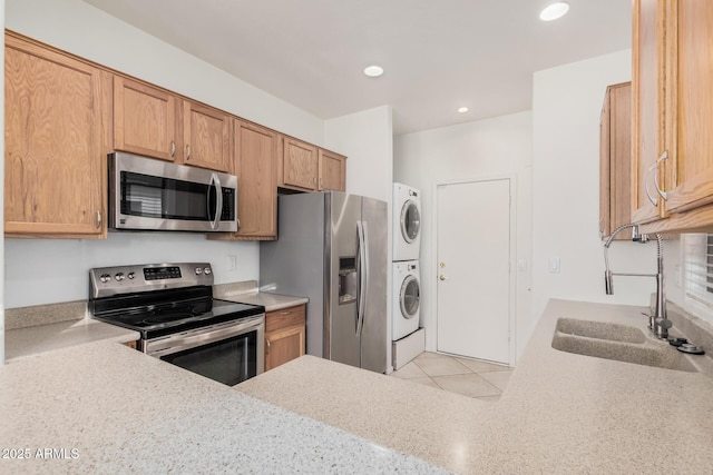 kitchen featuring stacked washer / drying machine, sink, appliances with stainless steel finishes, and light stone countertops