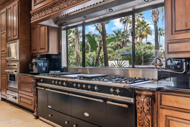 kitchen featuring oven, light tile floors, and dark stone countertops