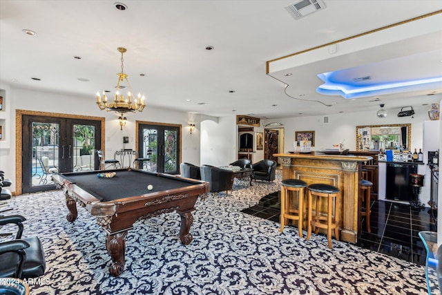 game room with an inviting chandelier, dark colored carpet, indoor bar, pool table, and french doors