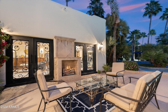 patio terrace at dusk with french doors and an outdoor fireplace