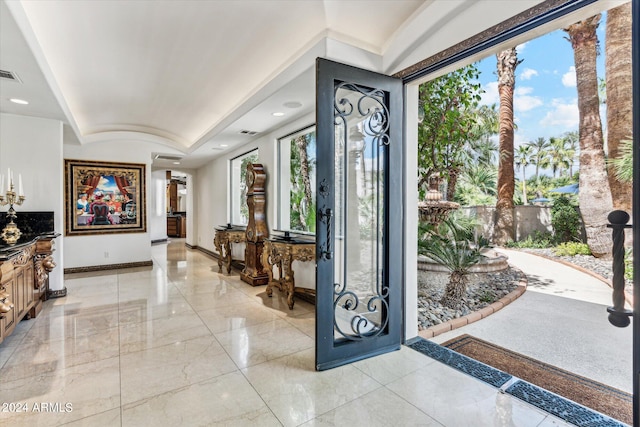 entryway featuring a tray ceiling and light tile floors