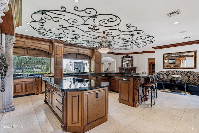 kitchen featuring light tile flooring, sink, ornamental molding, and an island with sink