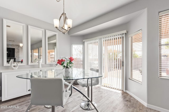 dining room featuring a wealth of natural light, light wood finished floors, baseboards, and an inviting chandelier