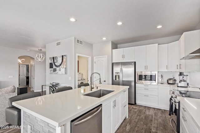 kitchen featuring an island with sink, appliances with stainless steel finishes, a sink, and visible vents