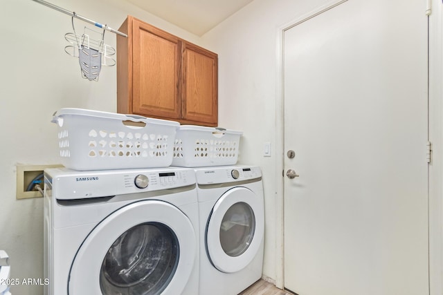 clothes washing area with independent washer and dryer and cabinet space