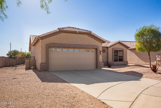 view of front facade featuring a tile roof, concrete driveway, stucco siding, and fence
