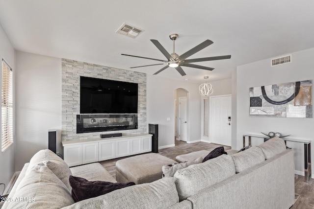 living room featuring wood finished floors, visible vents, arched walkways, and a ceiling fan