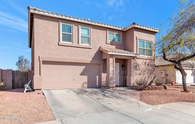 view of front of house featuring stucco siding, fence, a garage, driveway, and a tiled roof