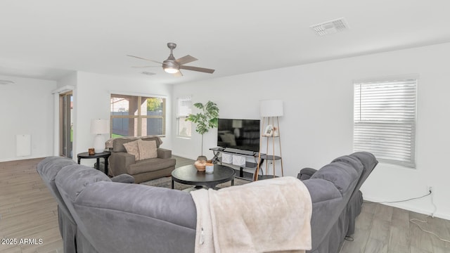 living room with a ceiling fan, light wood-type flooring, visible vents, and baseboards