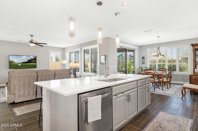 kitchen featuring a breakfast bar, sink, dishwasher, hanging light fixtures, and an island with sink