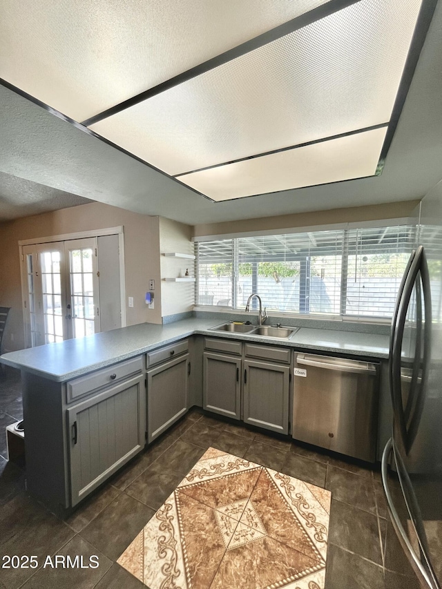 kitchen with a sink, appliances with stainless steel finishes, a peninsula, and a healthy amount of sunlight