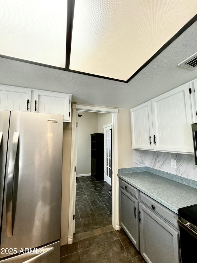 kitchen with freestanding refrigerator, tasteful backsplash, white cabinets, gray cabinets, and light countertops
