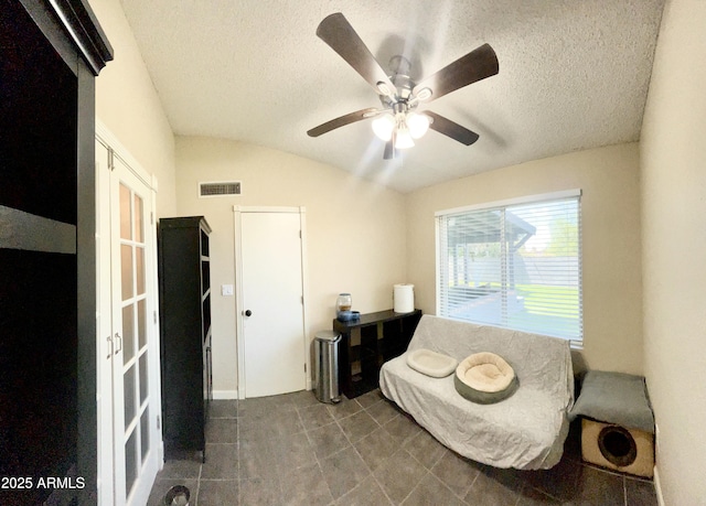 sitting room with lofted ceiling, visible vents, a textured ceiling, and ceiling fan