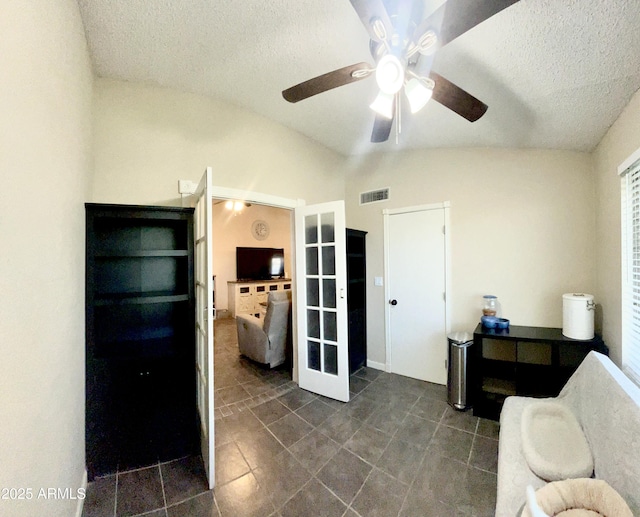 interior space featuring visible vents, dark tile patterned floors, ceiling fan, a textured ceiling, and lofted ceiling