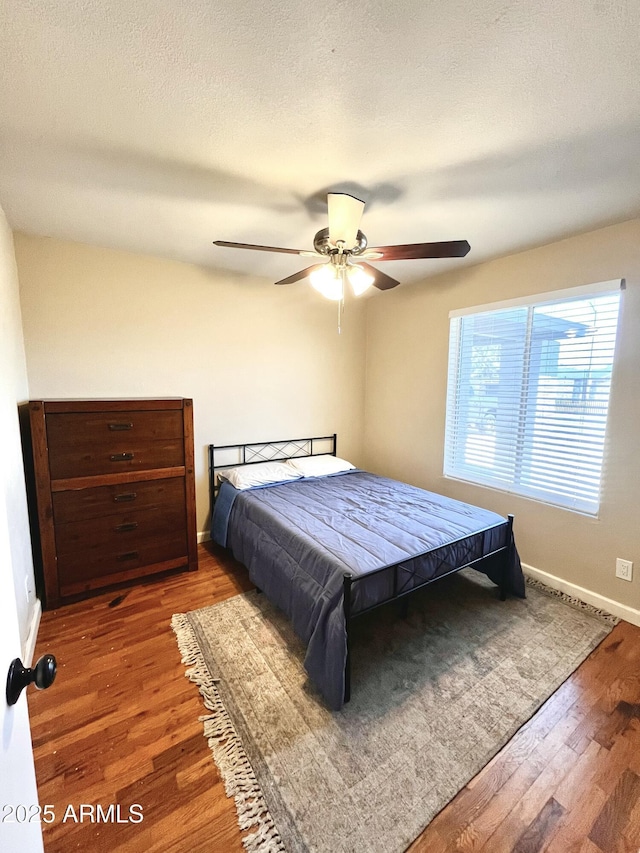 bedroom with baseboards, a ceiling fan, and wood finished floors