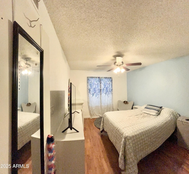 bedroom with ceiling fan, wood finished floors, and a textured ceiling