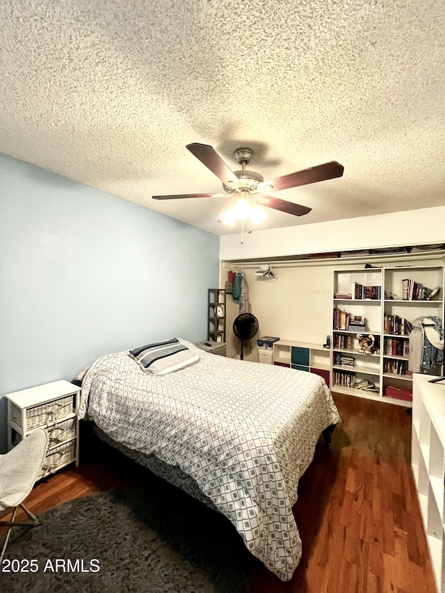 bedroom with a textured ceiling, a ceiling fan, and wood finished floors