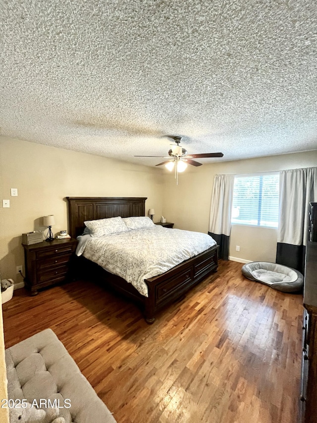 bedroom with a textured ceiling, wood finished floors, baseboards, and a ceiling fan