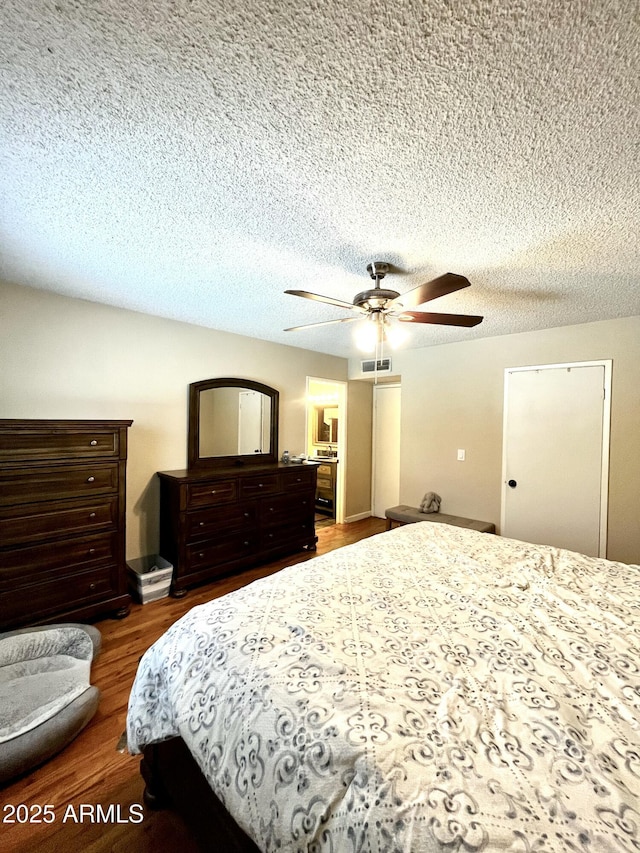 bedroom featuring a textured ceiling, wood finished floors, ceiling fan, and visible vents