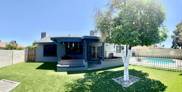 back of house featuring a patio area, a lawn, a chimney, a fenced backyard, and a fenced in pool